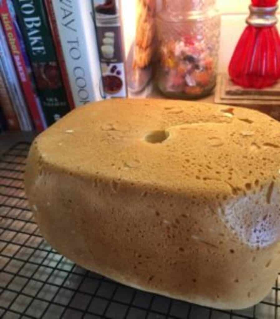 Finished loaf of baked white bread showing hole in the bottom from the bread machine.