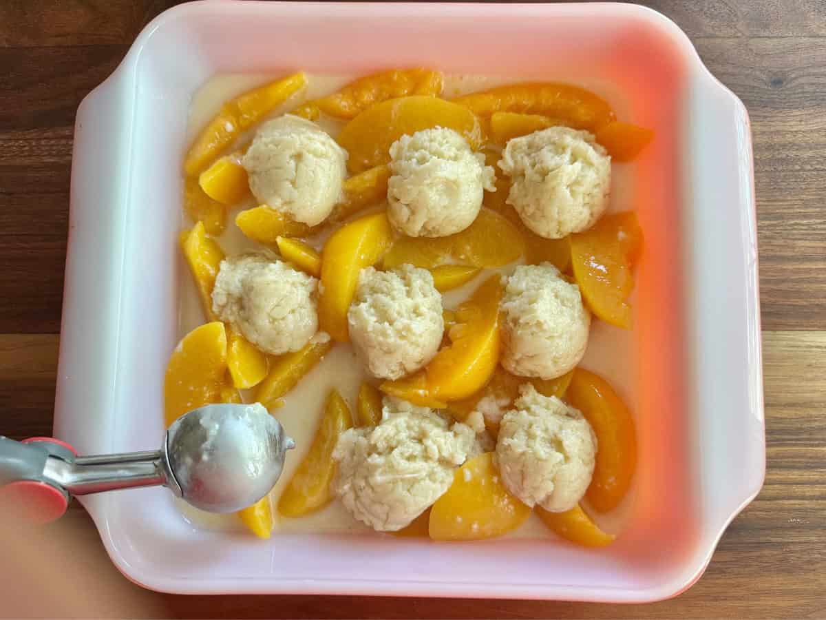 Dough mounds on top of peaches.