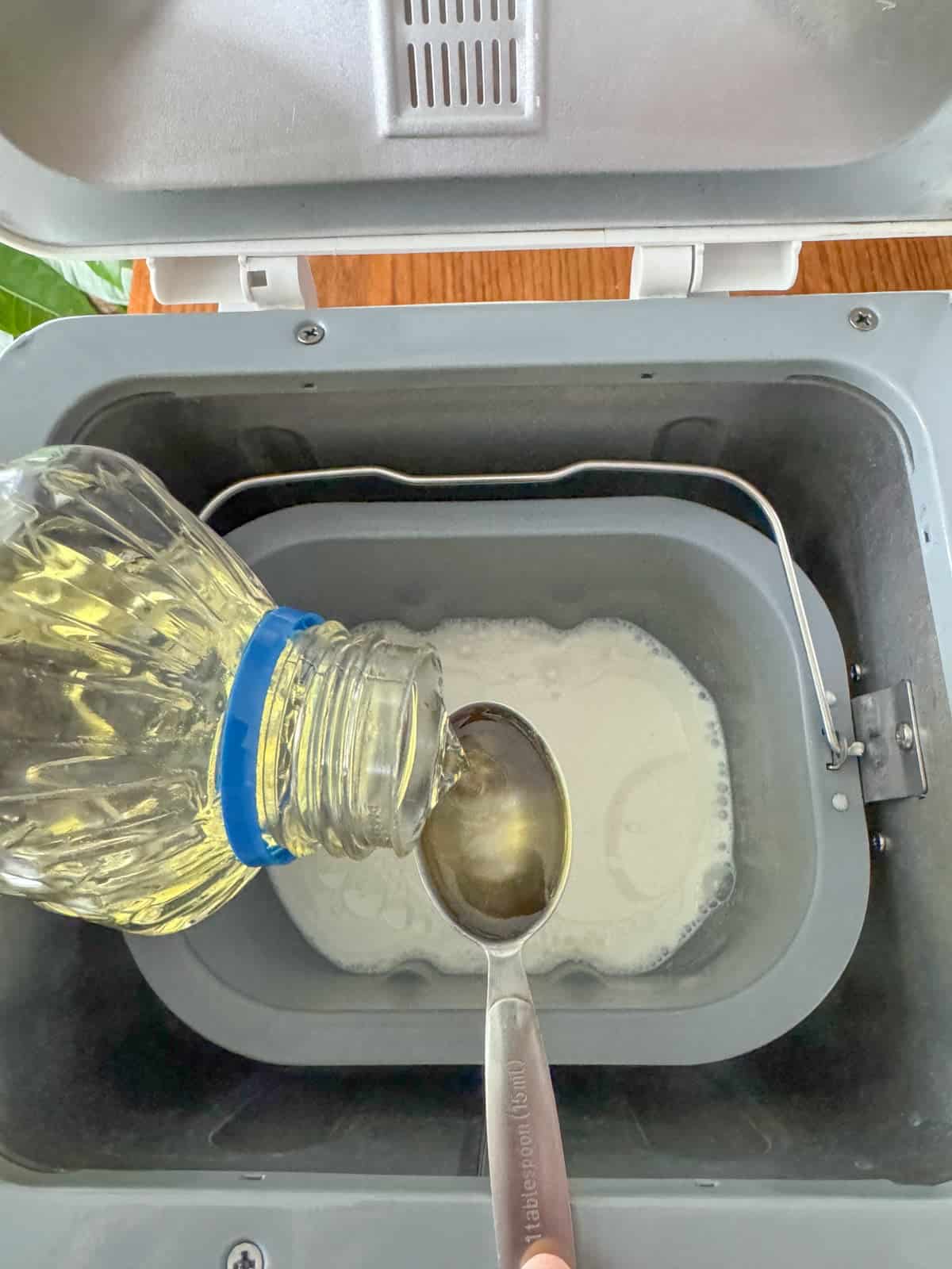 Adding oil to bread machine pan.