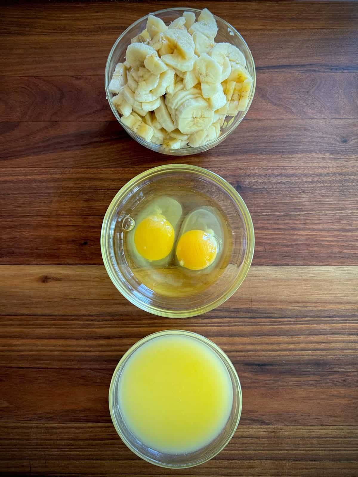 bowls of banana, eggs, and melted butter.