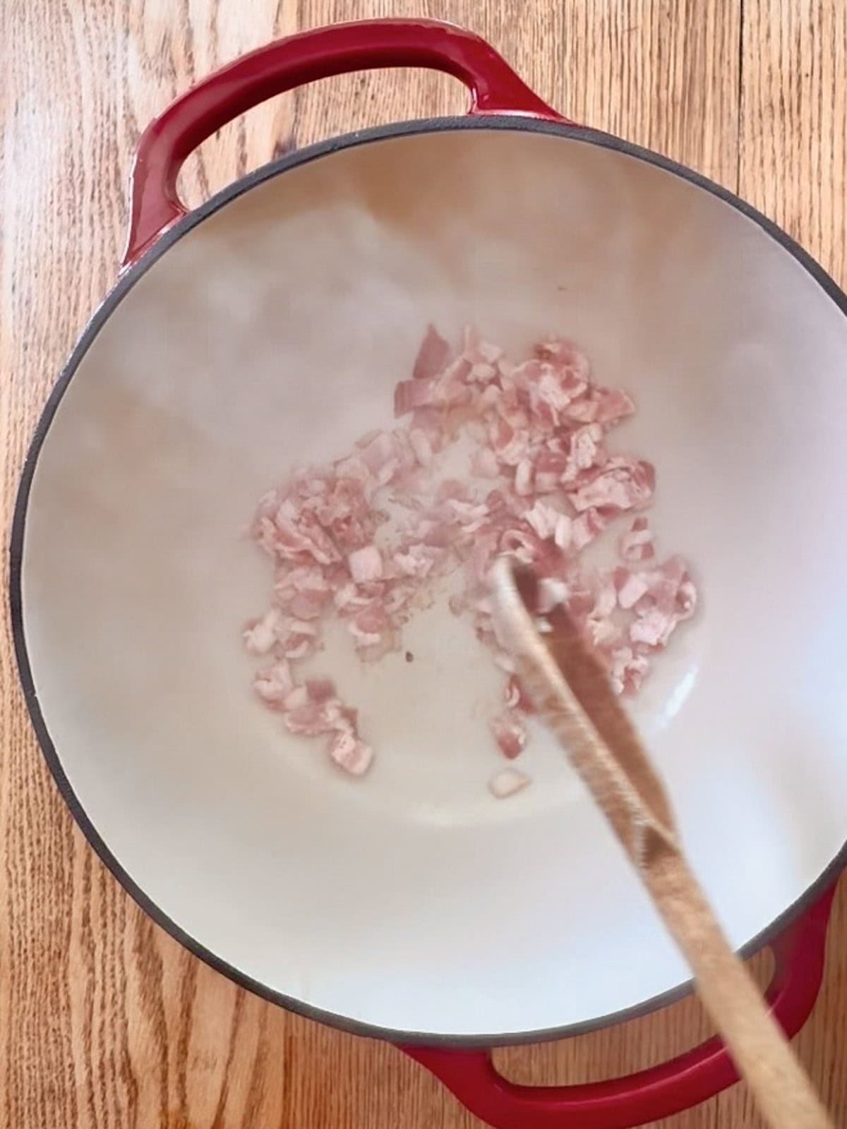 Chopped bacon cooking in a dutch oven.