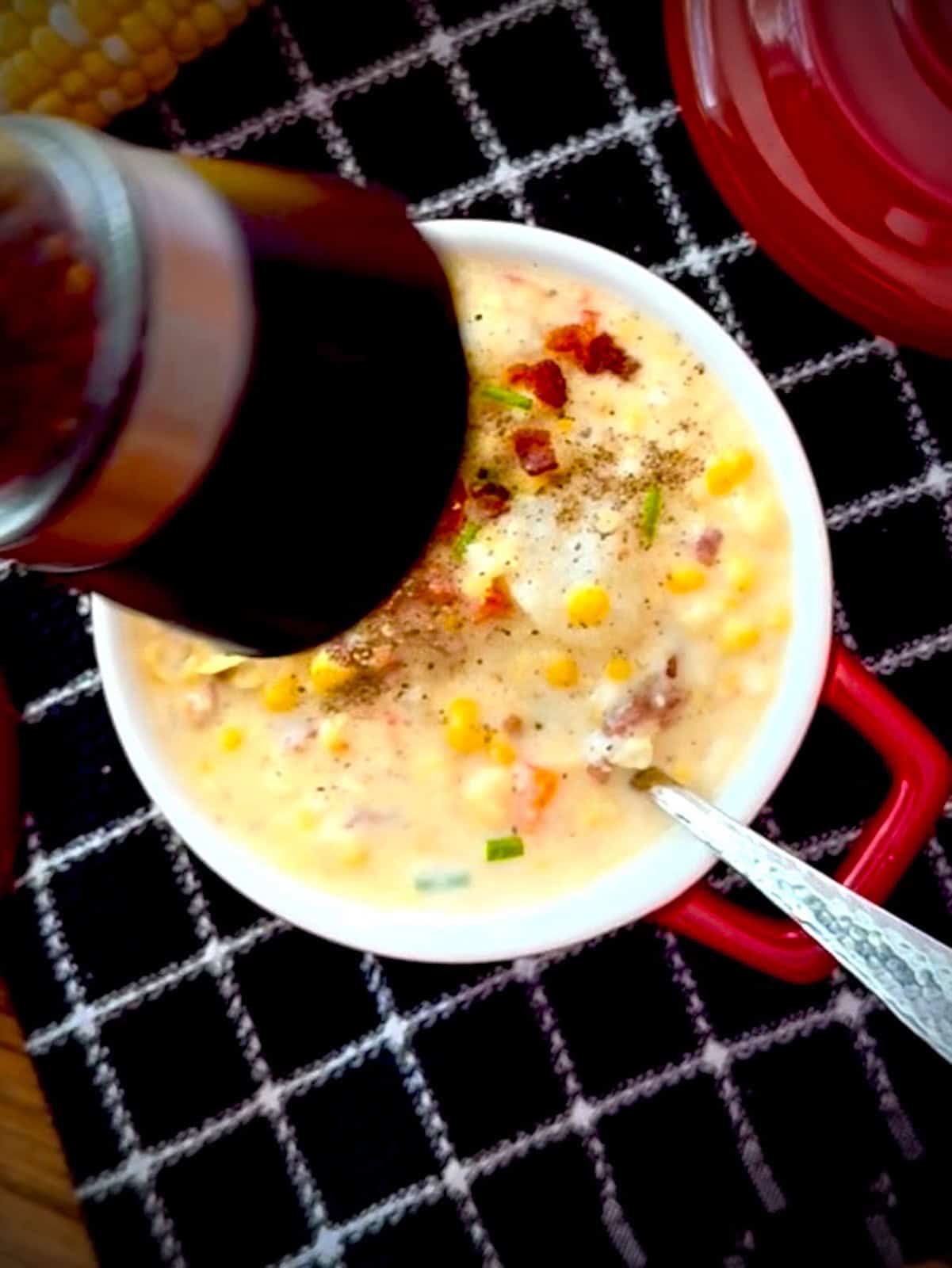 Grinding pepper over corn chowder.