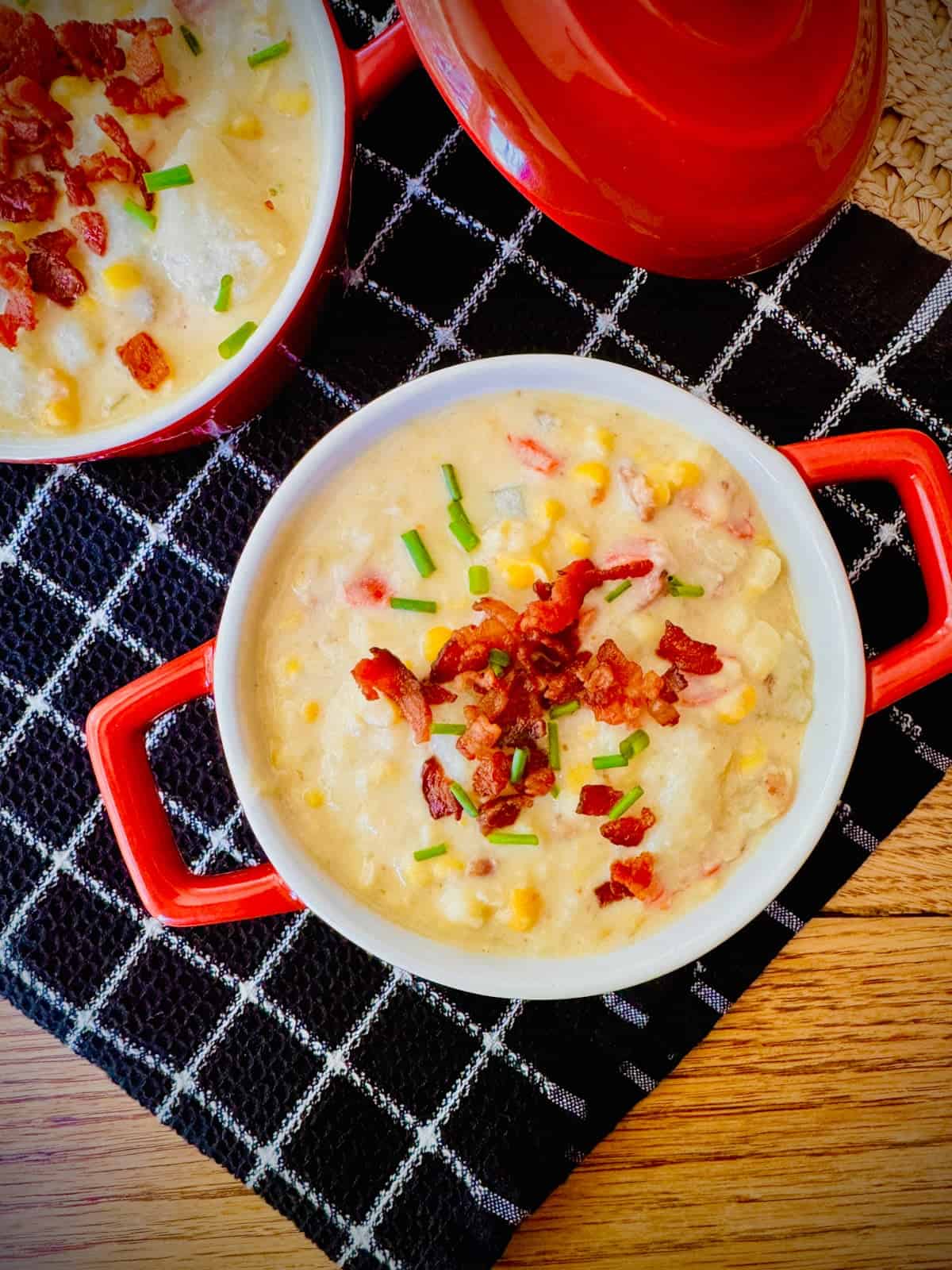 Bowl of corn chowder with bacon and chives on top.