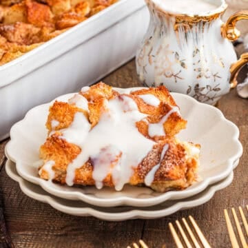 Baked bread pudding covered in white vanilla sauce.