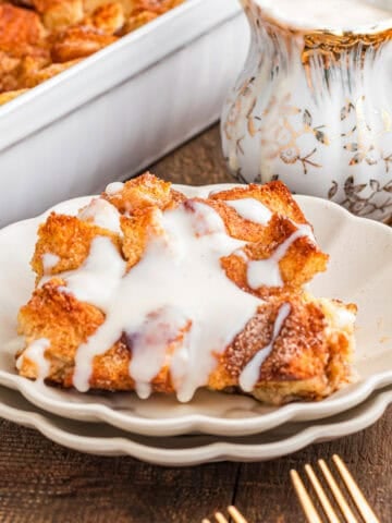 Baked bread pudding covered in white vanilla sauce.