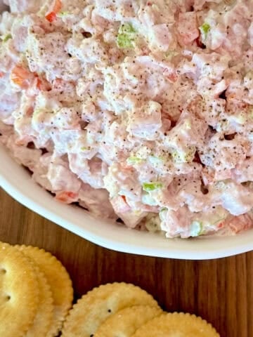 Bowl of ham salad with crackers in front.